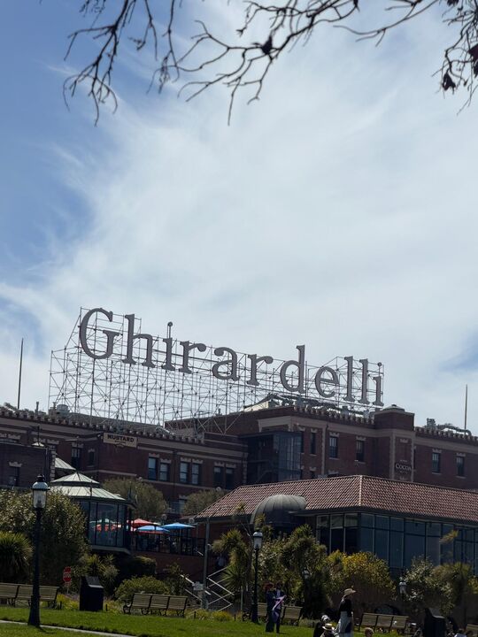 The Ghirardelli Square rooftop sign seen from the park on a clear afternoon