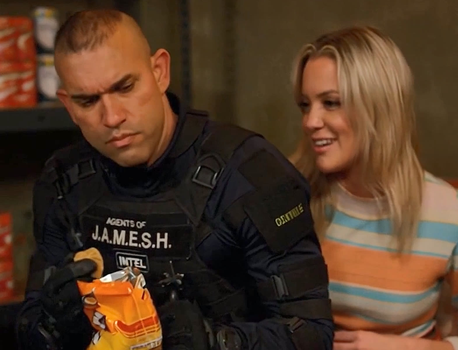 Commander examining chips bag while Night Shade smiles behind him